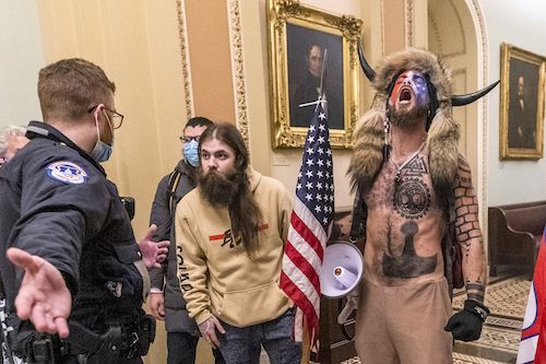 Qanon Shaman and other insurrectionsists confront a Capitol police officer