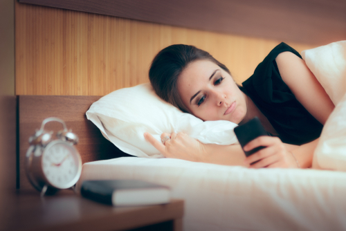 Woman Checking her Phone in Bed Upset girl reading messages on her Smartphone