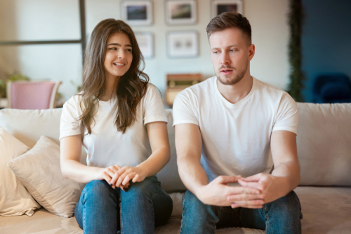 man and woman sitting on the sofa both looking embarrassed