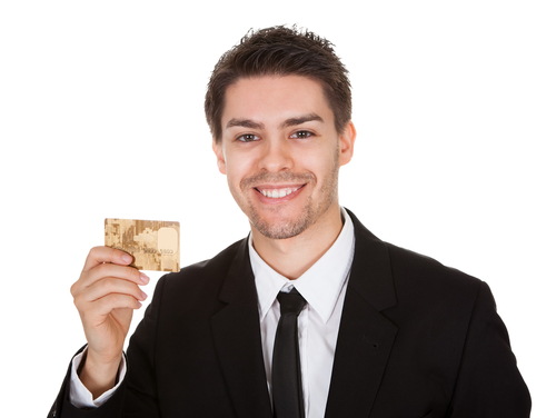 studio portrait on white of a smiling handsome young businessman holding up a credit card