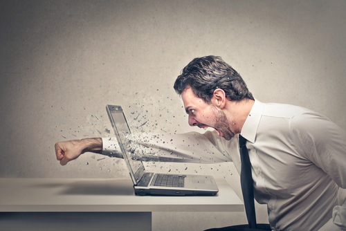 furious businessman punches through the screen of his laptop
