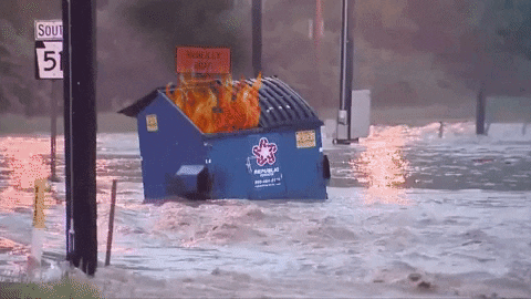 gif animado de un contenedor de basura flotando por una calle inundada, fuego superpuesto en el interior