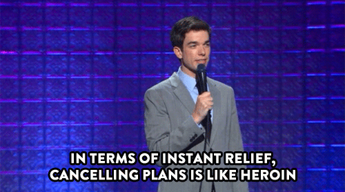 Animated gif of comedian John Mulaney doing stand up in front of a blue panel wall. Text reads: "In terms of instant relief, cancelling plans is like heroin."