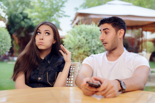 Attractive woman looks bored and frustrated listening to her boyfriend talk in an outdoor cafe